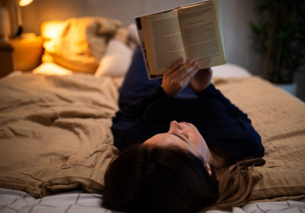 Person reading a book in bed.